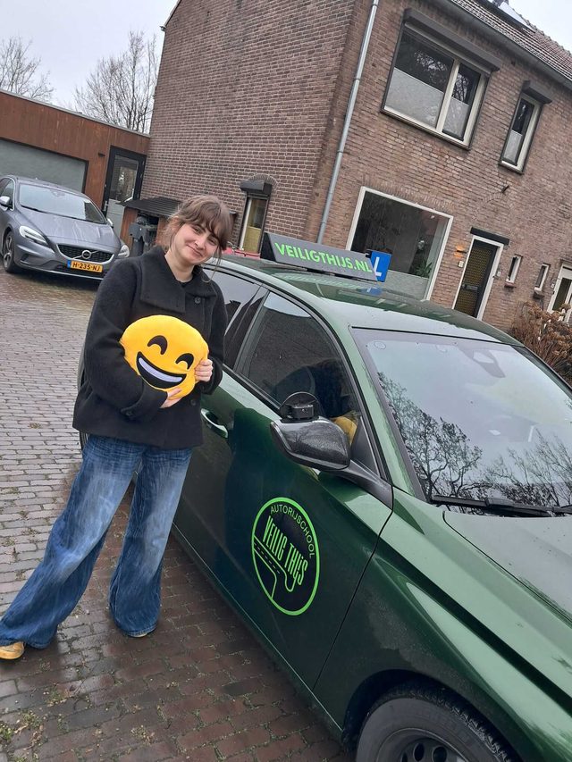 Geslaagde leerling naast de lesauto van Veilig Thijs